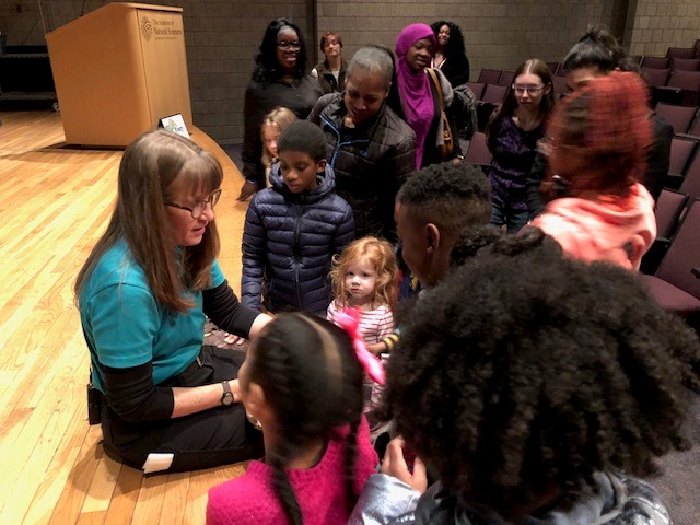 Elementary school students listening to a science academy worker
